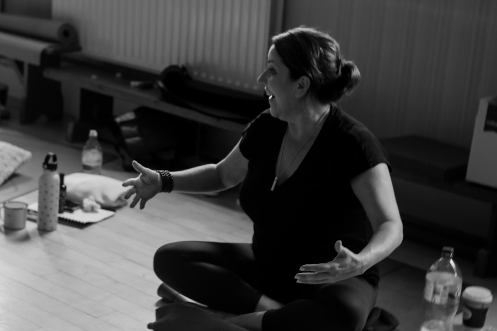 Black-and-white photograph of Mary teaching, seated cross-legged on a studio floor