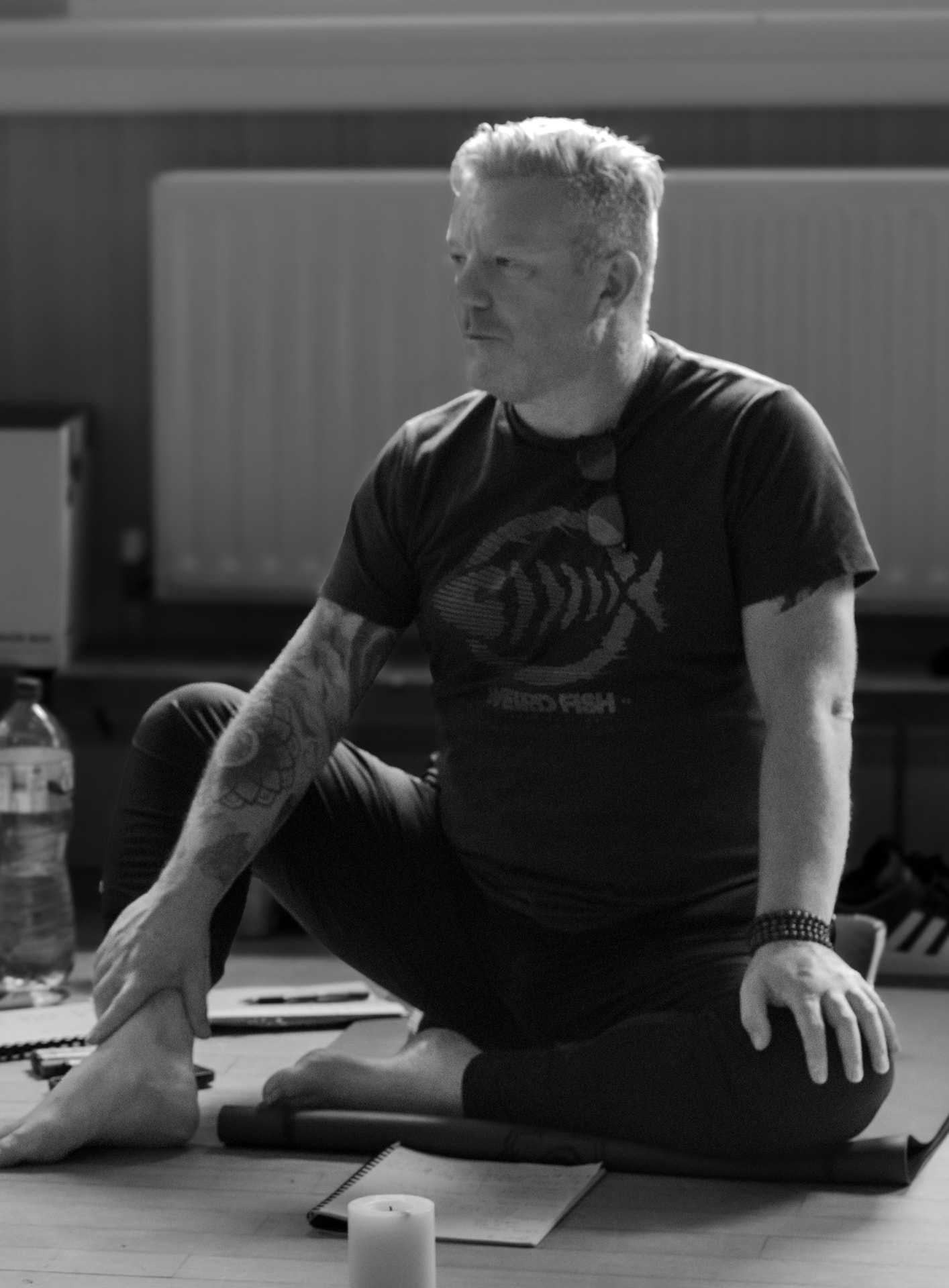Black-and-white photograph of Michael Connolly seated on a studio floor beside a candle