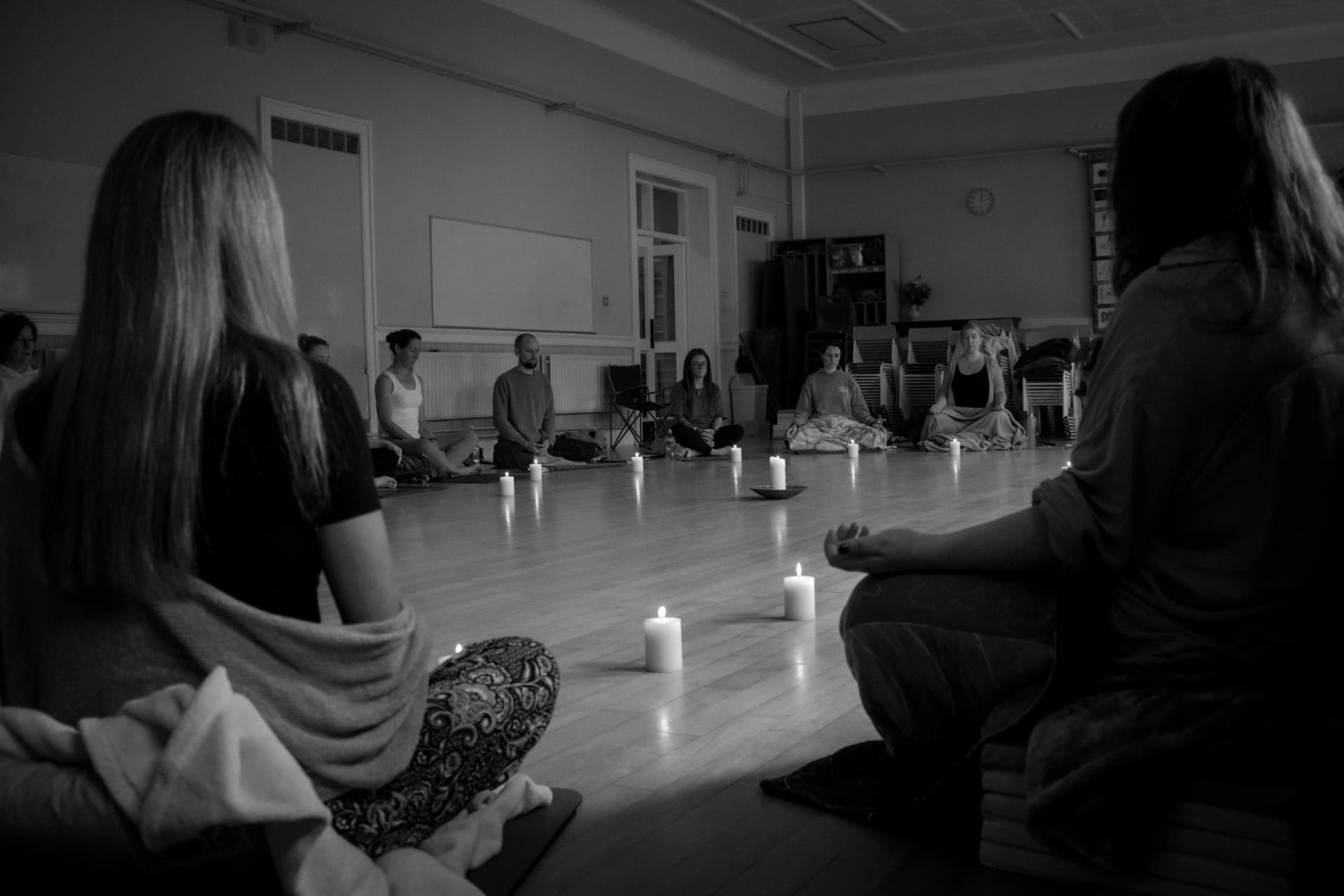 Black-and-white photograph of a group seated in a candlelit meditation circle