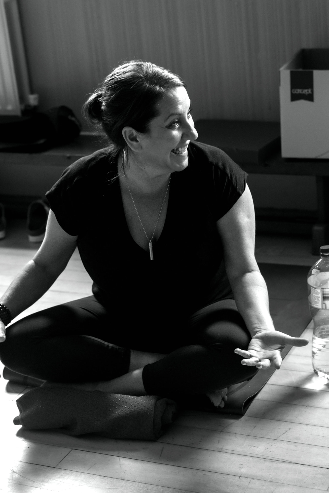 Black-and-white photograph of Mary Dowling seated cross-legged, laughing, on a studio floor